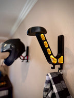 Black and gold helmet wall mount with a helmet and jacket in the background.