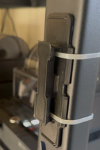 Close-up of a metal bracket with a white strap on a blurred background