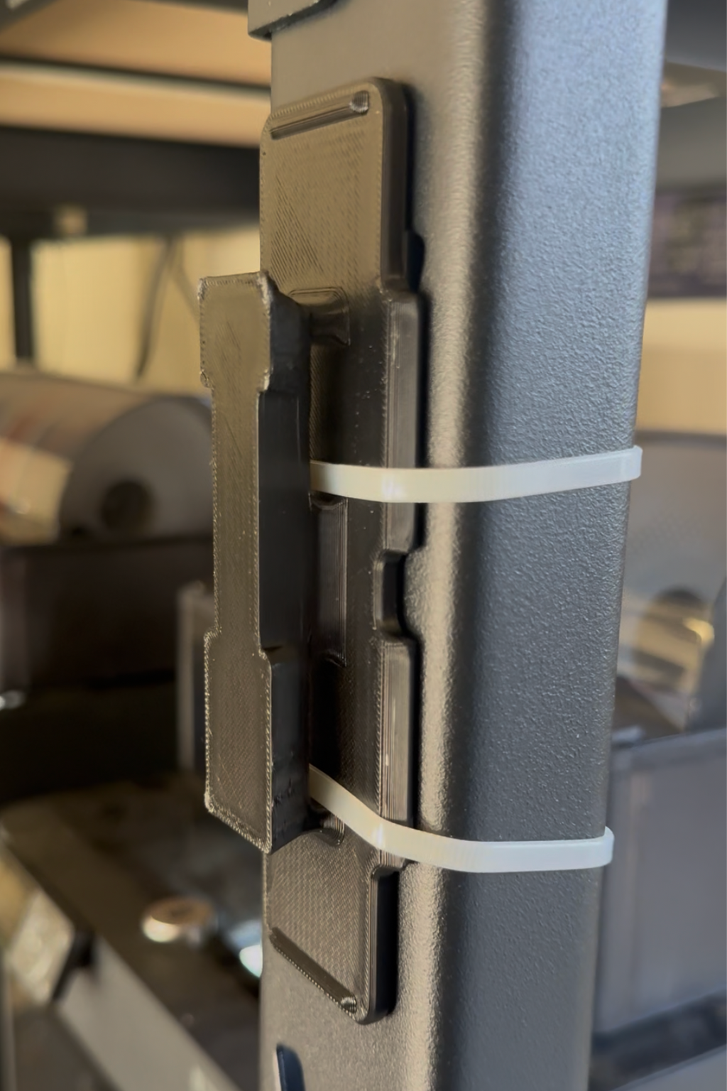 Close-up of a black metal hinge with a white band on a blurred background