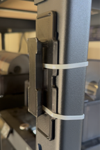 Close-up of a black metal hinge with a white band on a blurred background