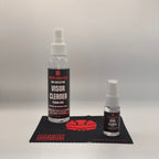Two bottles of McCoy Industries Anti-Reflective Visor Cleaner, one large and one small, displayed on a black branded microfiber cloth against a light gray background.